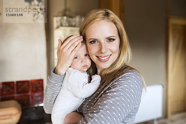 Porträt der lächelnden Mutter mit dem Baby zu Hause