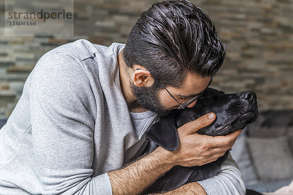 Mann kuschelt mit seinem Hund zu Hause