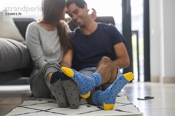 Junges Paar in gemusterten Socken entspannt zu Hause