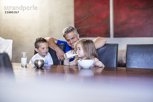 Glücklicher Vater mit sitzenden Kindern beim Frühstück am Tisch