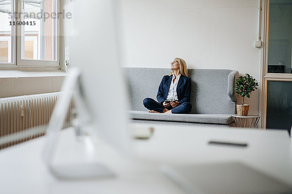 Entspannte Geschäftsfrau auf der Couch sitzend