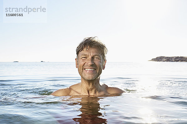 Porträt eines glücklichen Mannes beim Baden im Meer