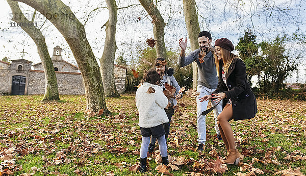 Familienspiel mit Herbstblättern im Park