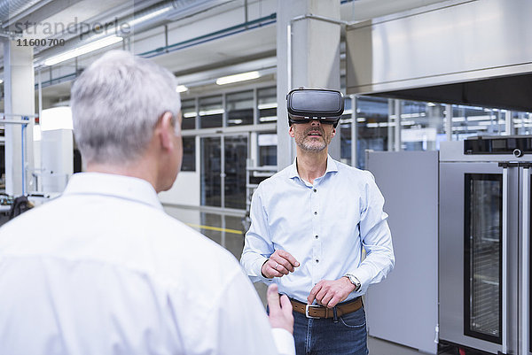 Zwei Manager  die mit einer VR-Brille in der Firma stehen.