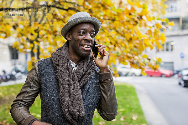 Porträt eines stilvollen Mannes am Telefon im Herbst