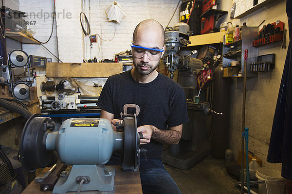 Mann mit gemischter Rasse benutzt Maschinen in einer Werkstatt