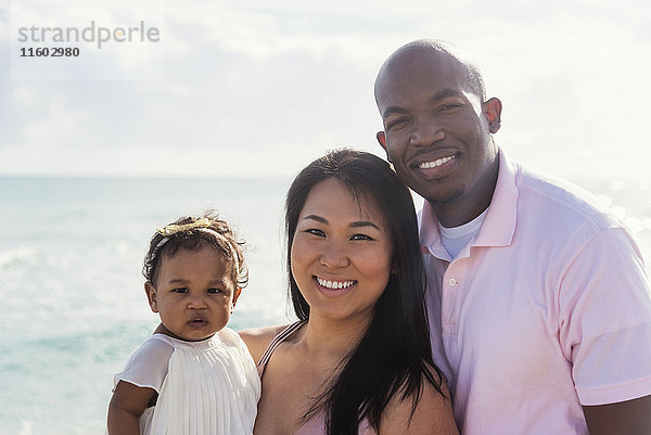 Paar posiert in der Nähe des Ozeans mit seiner kleinen Tochter