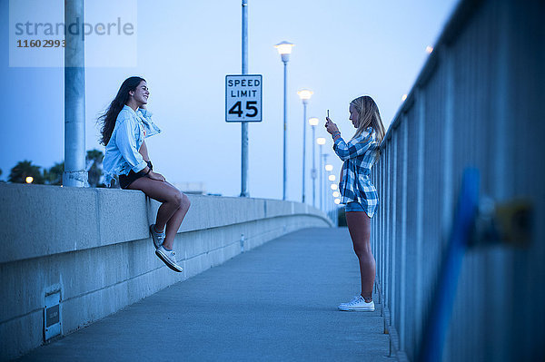 Teenager-Mädchen fotografiert Freund an der Wand sitzend