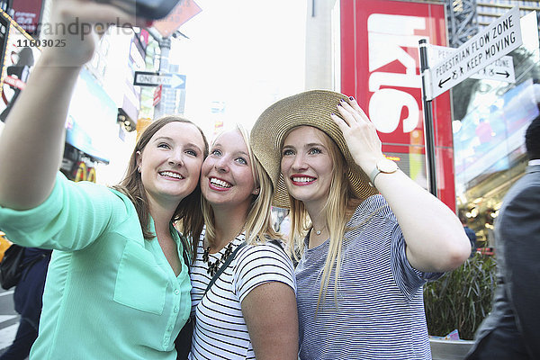 Lächelnde kaukasische Frau  die für ein Selfie mit ihrem Handy in der Stadt posiert