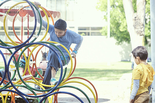 Hispanische Jungen klettern auf dem Spielplatz auf eine Struktur