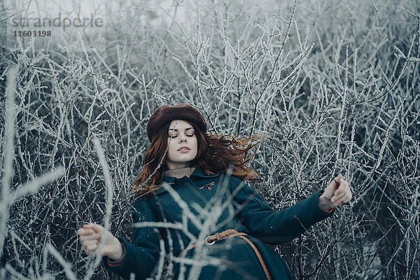 Kaukasische Frau liegt auf Zweigen im Winterfeld