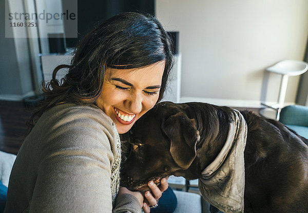 Gemischtrassige Frau umarmt Hund