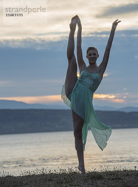 Kaukasische Ballerina tanzt am Strand bei Sonnenuntergang