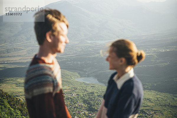 Kaukasisches Paar steht auf einem Berg über einem Tal