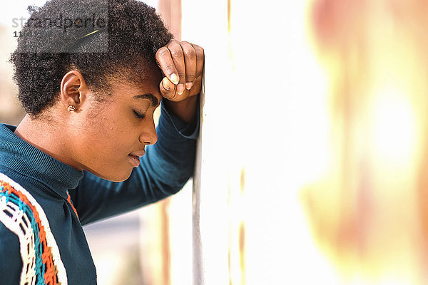 Nachdenkliche afroamerikanische Frau  die sich an die Wand lehnt