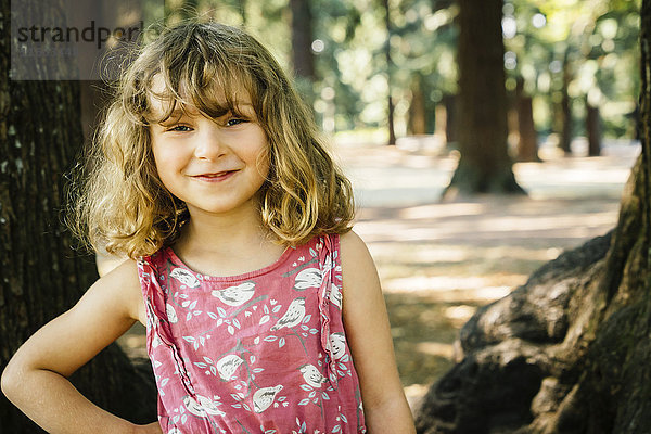 Porträt eines lächelnden kaukasischen Mädchens in der Nähe von Bäumen