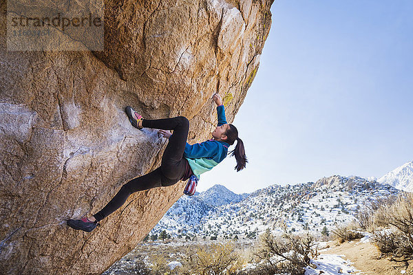 Gemischtrassiges Mädchen klettert auf Felsen