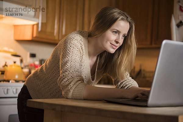 Lächelnde Frau mit Laptop in der heimischen Küche