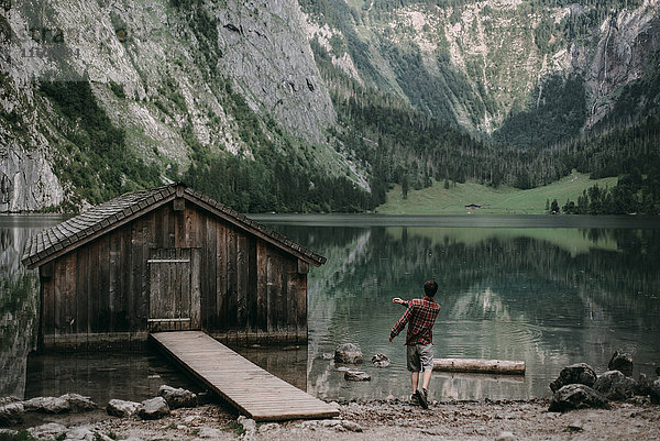 Kaukasischer Mann  der Steine in einem Bergsee springt