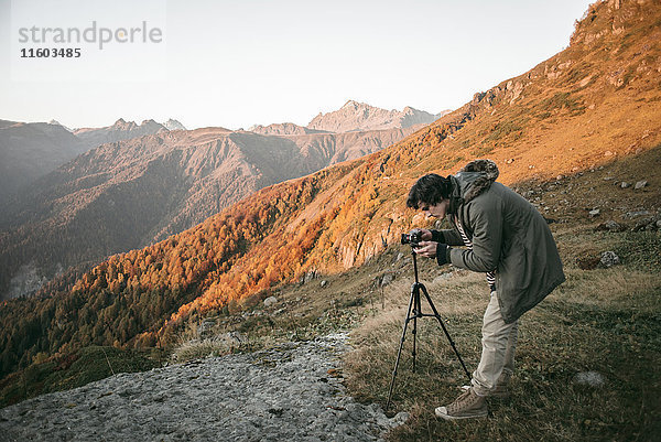 Kaukasischer Mann fotografiert Tal vom Berg aus