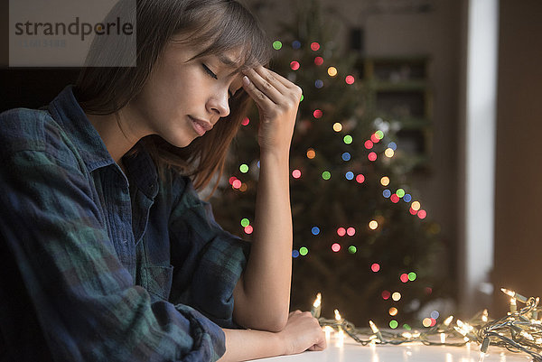 Gemischtrassige Frau mit Kopfschmerzen in der Nähe des Weihnachtsbaums
