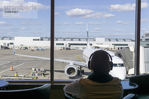 Passagier hört Kopfhörer am Flughafen