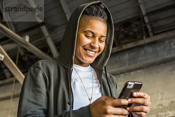 Androgyne gemischtrassige Frau  die eine SMS auf ihrem Handy schreibt
