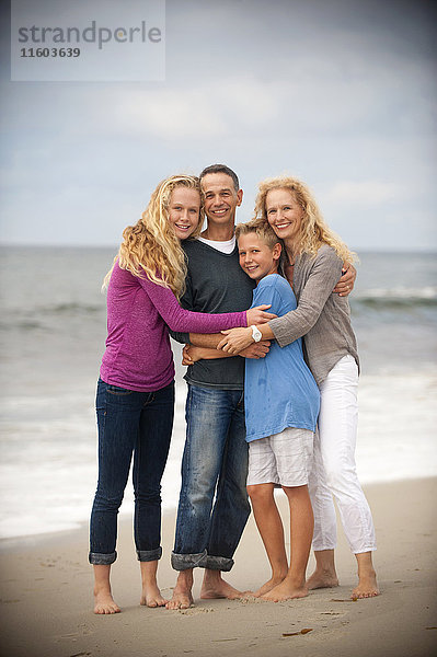 Porträt einer lächelnden Familie  die sich am Strand umarmt