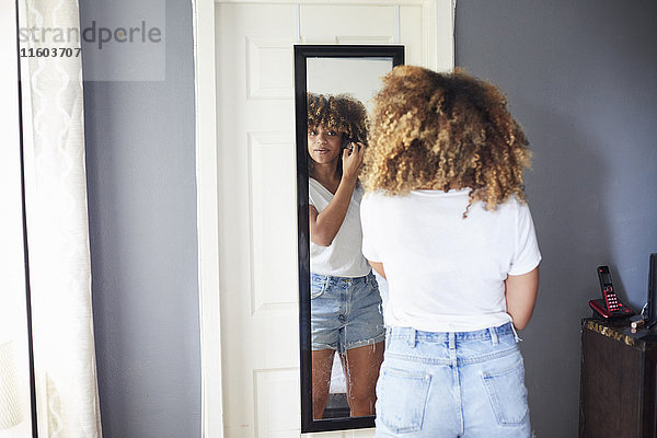 Schwarze Frau begutachtet Haare im Spiegel