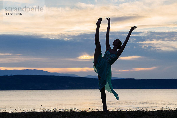 Kaukasische Ballerina tanzt am Strand bei Sonnenuntergang