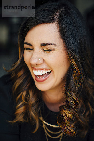 Porträt einer lachenden gemischtrassigen Frau mit gepiercter Nase