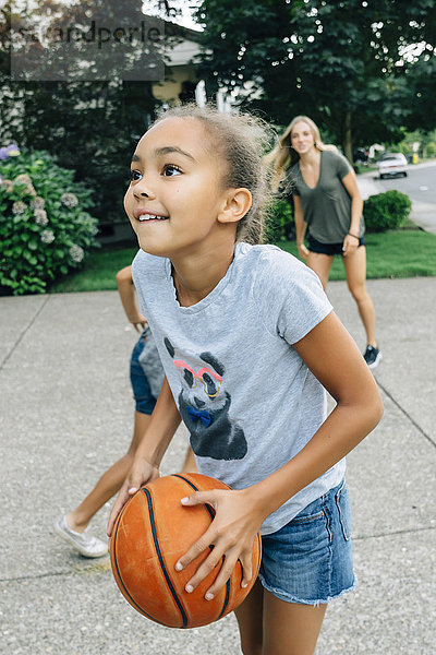 Mutter und Töchter spielen Basketball in der Einfahrt
