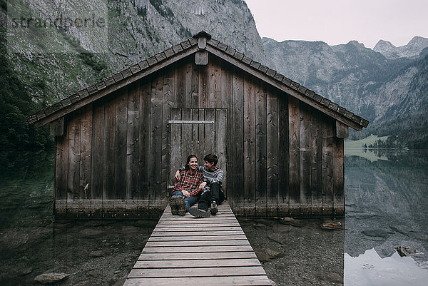 Kaukasisches Paar sitzt auf dem Steg einer abgelegenen Hütte