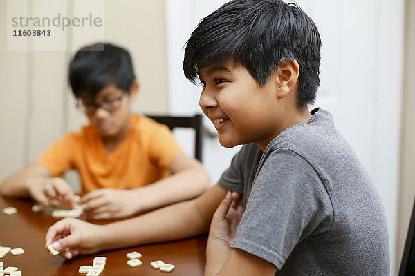 Amerikanische Jungen spielen ein Buchstabierspiel am Tisch