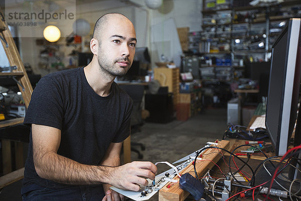 Gemischtrassiger Mann arbeitet mit Elektronik in einer Werkstatt