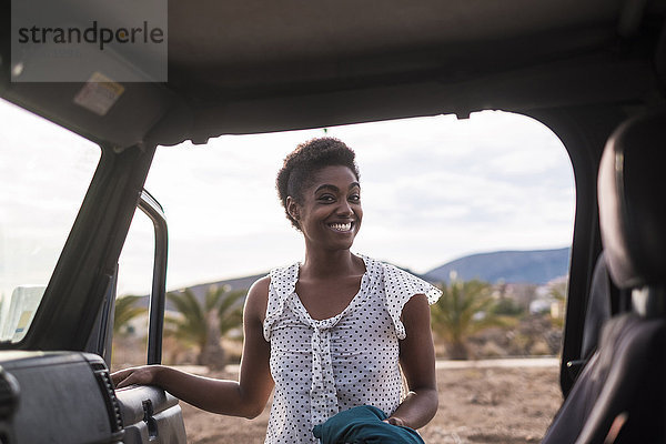 Lächelnde afroamerikanische Frau öffnet Autotür