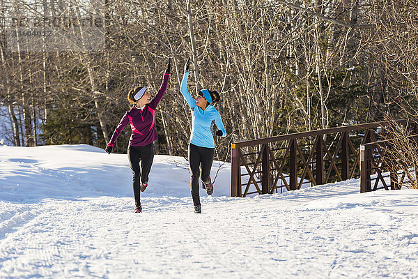 Frauen beim Laufen und Feiern im Schnee im Winter