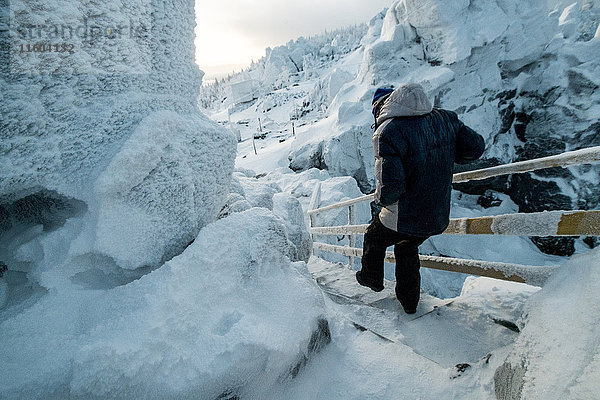 Kaukasischer Mann beim Abstieg über eine Schneetreppe in der Nähe von Felsen