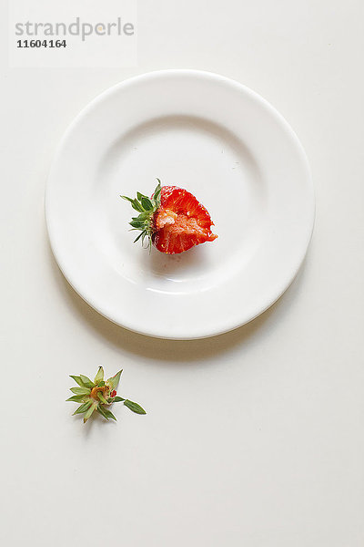 Angebissene Erdbeere auf weißem Teller