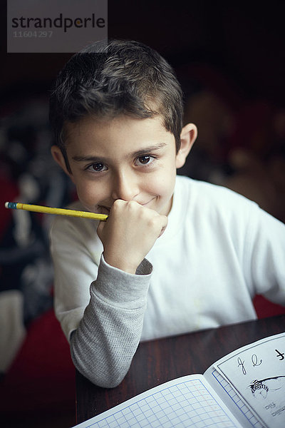 Lächelnder hispanischer Junge übt das Schreiben des Alphabets
