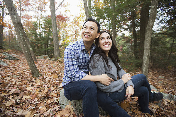 Paar sitzt auf einem Felsen im Wald im Herbst