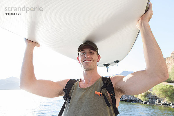 Kaukasischer Mann mit Paddleboard am Fluss