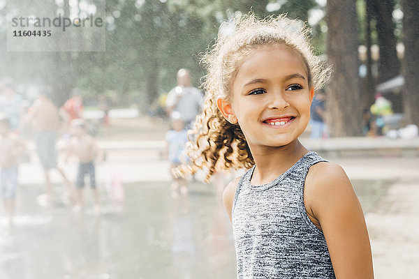 Mixed Race Mädchen lächelnd im Park in der Nähe von Springbrunnen