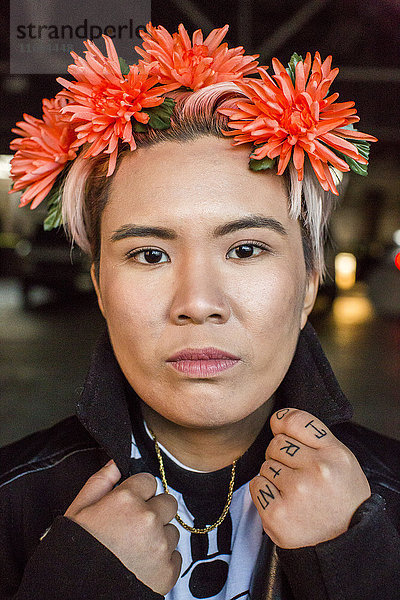 Porträt einer ernsten androgynen asiatischen Frau mit Blumen im Haar
