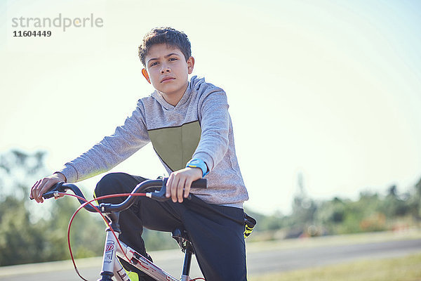Ernster hispanischer Junge posiert auf dem Fahrrad