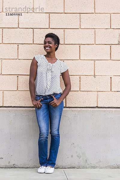 Lächelnde afroamerikanische Frau posiert in der Nähe einer Betonwand