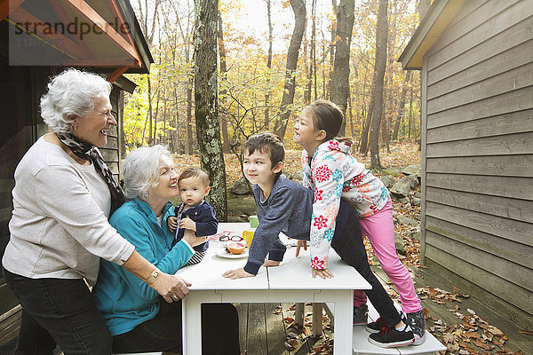 Großmütter spielen mit Enkelkindern am Frühstückstisch im Freien