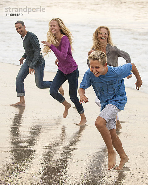 Lächelnde Familie beim Laufen am Strand