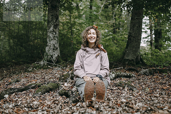 Kaukasische Frau sitzt im Herbst Blätter im Wald