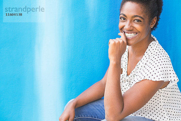 Afroamerikanische Frau lächelnd in der Nähe der blauen Wand